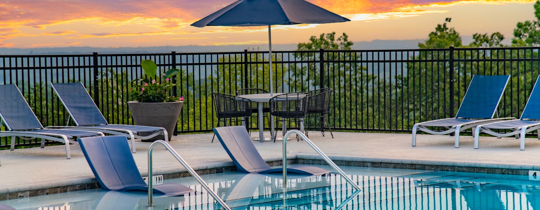 View of The Laurent at Carolina Forest's community pool with ample seating at sunset